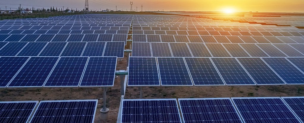 rows of ground mounted solar panels with a rising sun in the background